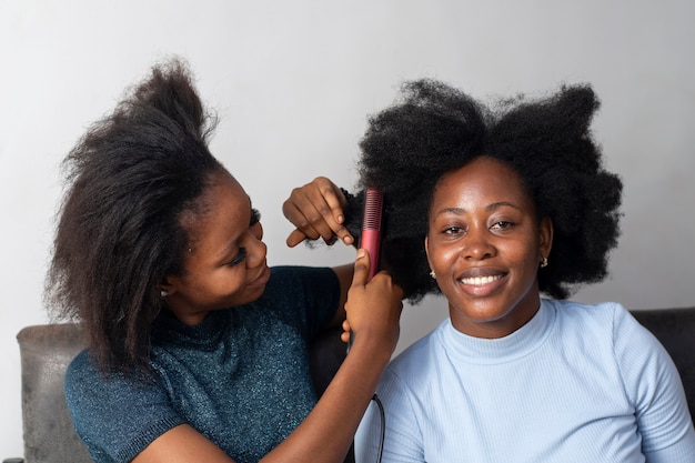 Stilista donna che si prende cura dei suoi capelli afro cliente