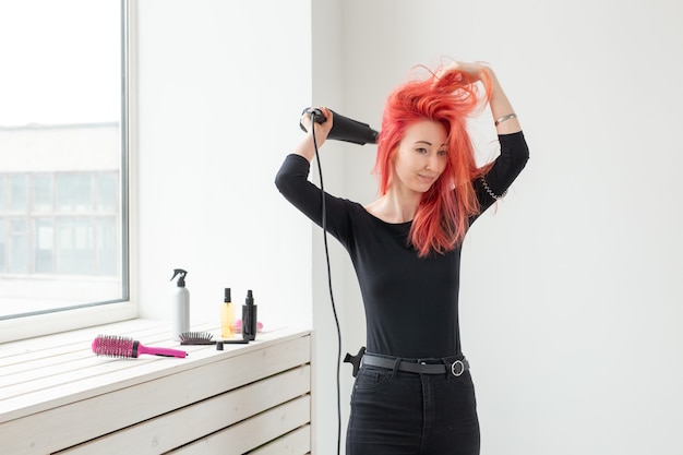 Stilista, moda, parrucchiere, concetto di persone - donna che asciuga i capelli colorati.