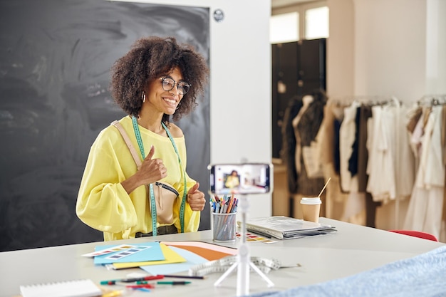 Stilista professionista afroamericano con conduce lezioni online a tavola con tavolozze di colori