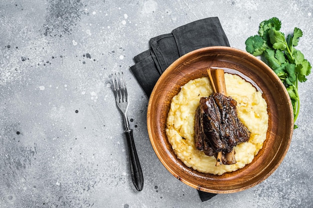 Stinco di agnello brasato sulla purè di patate in un piatto Sfondo grigio Vista dall'alto Spazio di copia