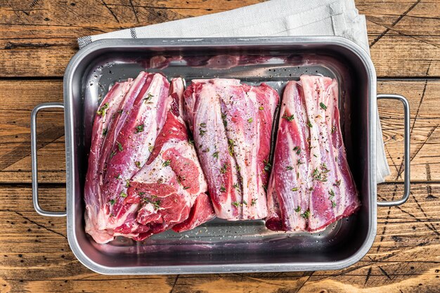 Stinco di agnello marinato con erbe, spezie e timo Carne di montone pronta per la cottura Sfondo in legno Vista dall'alto