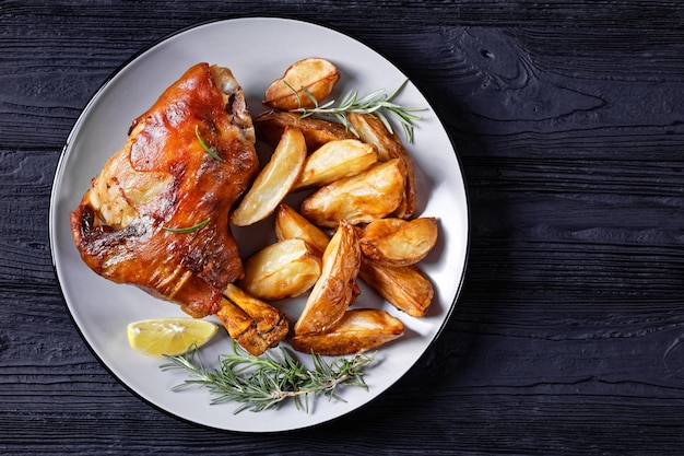 Stinco di maiale arrosto con patate su un piatto