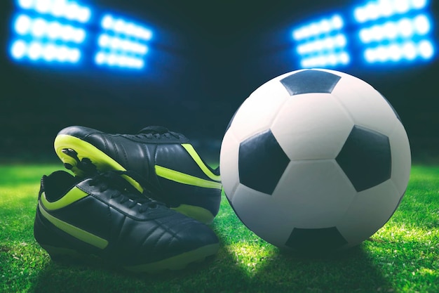 Stivale da calcio e palla sul campo all'interno di uno stadio girato di notte