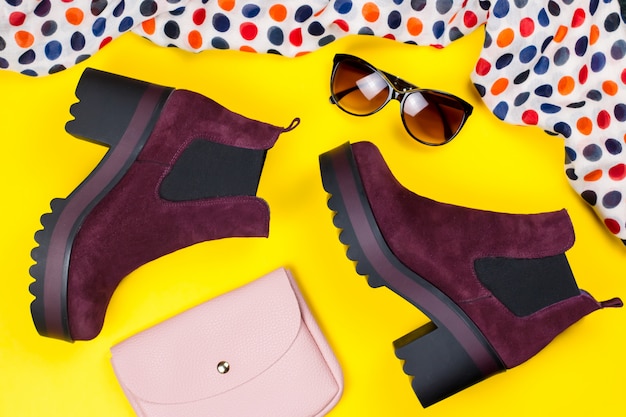 Stivaletti eleganti in camoscio viola, borsa rosa, occhiali da sole e sciarpa stampata
