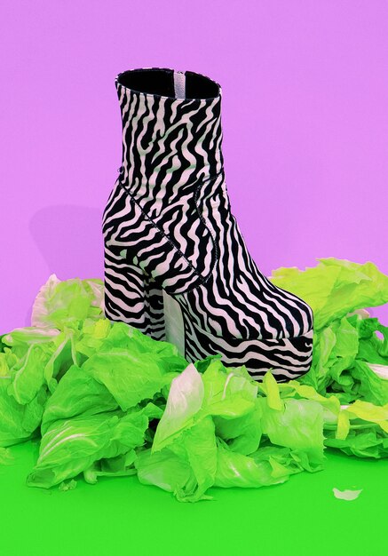 Stivali alla moda con stampa zebrata con sfondo di insalata verde fresca. Cibo sano, vegano, dieta, calorie, concetto minimo ecologico