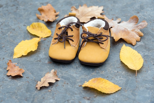 Stivali da bambino nella foresta. Scarpe per bambini con foglie di autunno all'aperto.