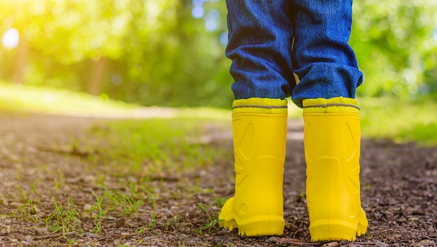 Stivali di gomma gialli ai piedi del bambino. Scarpe per tempo umido.
