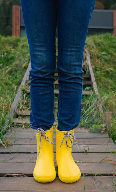 Stivali di gomma gialli sullo sfondo di erba bagnata Camminare sotto la pioggia Camminare in campagna con gli stivali