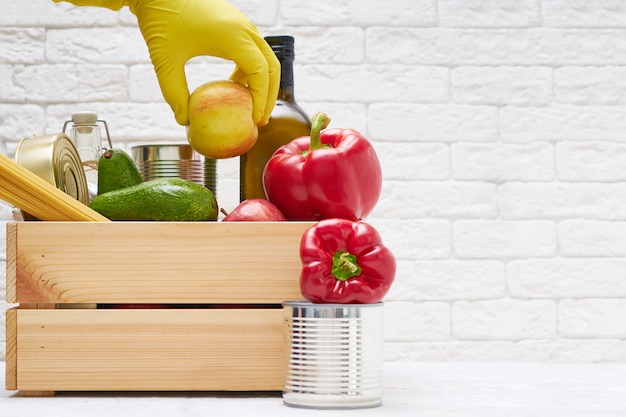 Stock alimentari in una scatola di legno. Verdure, olio, frutta, cibo in scatola, pasta. Donazione, consegna di cibo, coronavirus