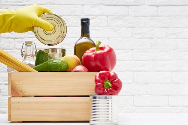 Stock alimentari in una scatola di legno. Verdure, olio, frutta, cibo in scatola, pasta. Donazione, consegna di cibo, coronavirus