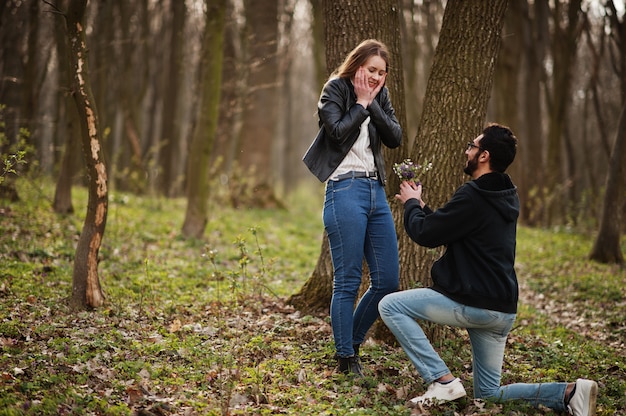 Storia d'amore di cool coppia multirazziale nella foresta di primavera. Proposta di matrimonio uomo arabo con ragazza europea.