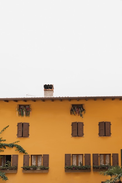 Storica architettura italiana Vecchio edificio rustico europeo tradizionale con pareti colorate arancioni persiane e finestre in legno Concetto estetico di viaggio per le vacanze estive