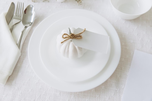 Stoviglie e decorazioni per la tavola del Ringraziamento Cartolina bianca vuota sul mockup del tavolo