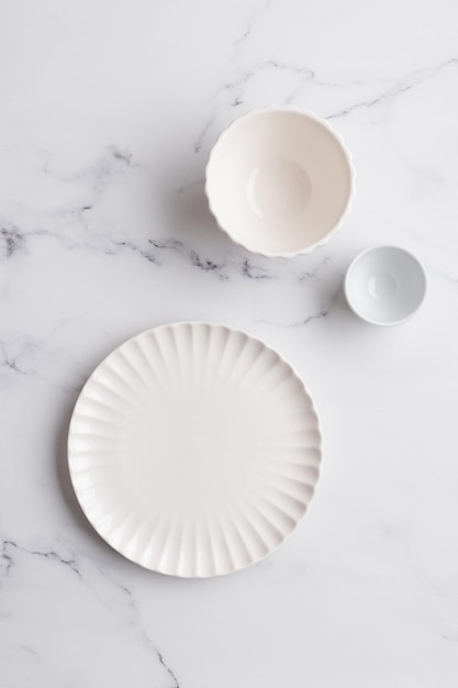 Stoviglie vuote piatto bianco una ciotola e una tazza sul tavolo bianco come sfondo per un piatto foodbackground