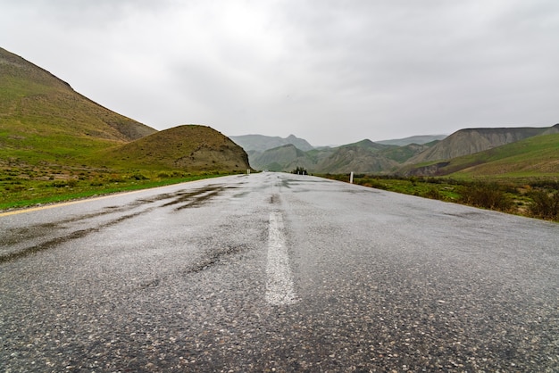 Strada asfaltata bagnata in zona montuosa