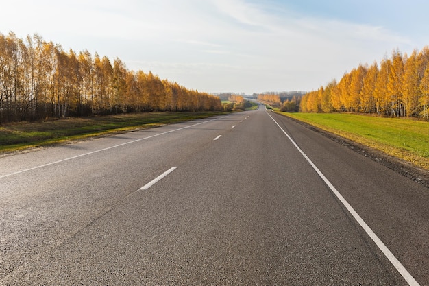 Strada asfaltata che si estende oltre l'orizzonte paesaggio rurale in autunno soleggiato autostrada