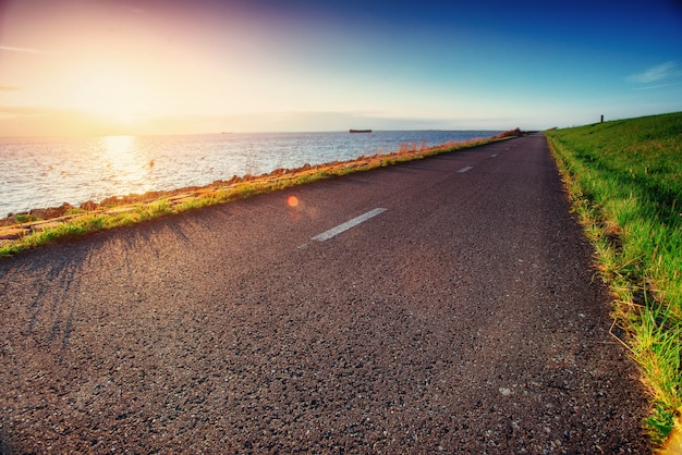 Strada asfaltata lungo il mare al tramonto