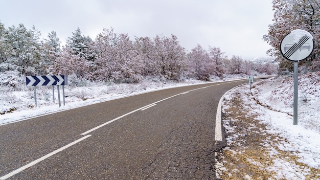 Strada asfaltata per la montagna innevata con segnali stradali consentiti il sorpasso. Madrid.