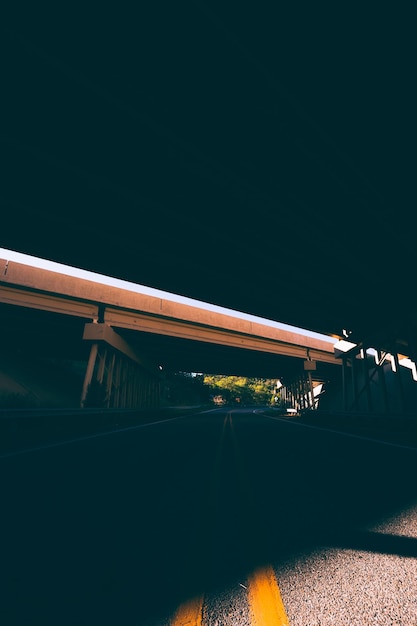 Strada asfaltata sotto un ponte di cemento fotografia urbana di notte