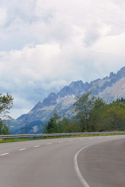 Strada asfaltata sullo sfondo di alte catene montuose