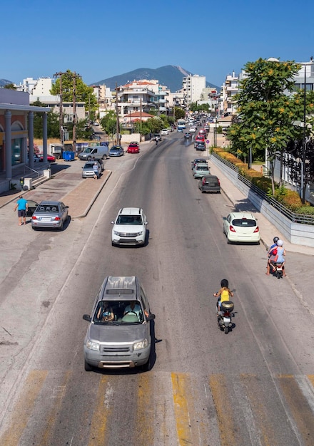 Strada centrale con auto, motociclette e tipica architettura greca in una soleggiata giornata estiva in Grecia