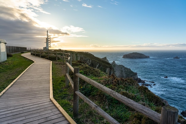 Strada che conduce al faro situato in cima alla scogliera di fronte al mare al tramonto Asturias Spagna