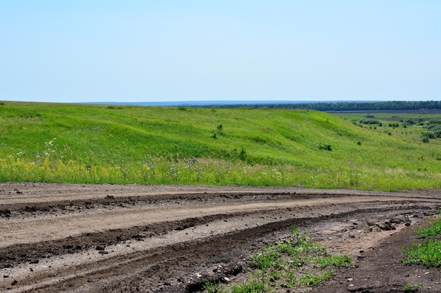 strada di campagna sporca con tracce di pneumatici con verdi colline e cielo blu sullo sfondo