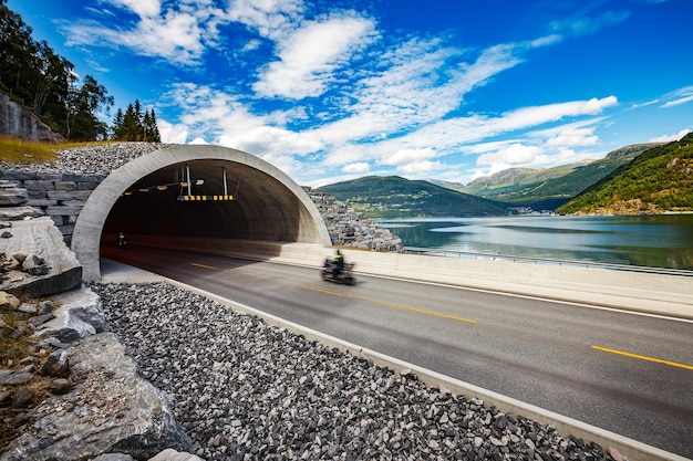 Strada di montagna in Norvegia. L'ingresso del tunnel. Motociclista che corre in pista nel tunnel