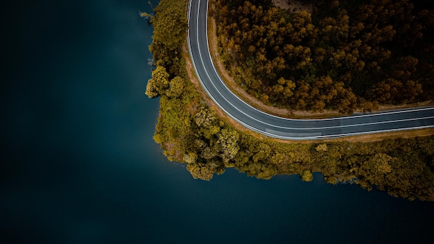 STRADA DI MONTAGNA tortuosa CON LAGO DA VISTA AEREA CON DRONE