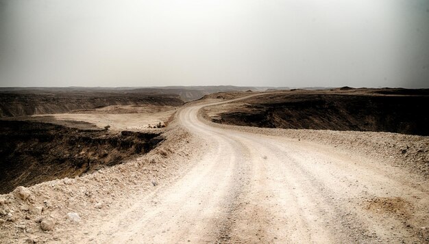 Strada di terra in mezzo al paesaggio contro il cielo