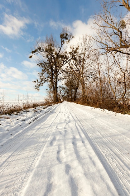 Strada innevata, sulla quale c'erano tracce dell'auto da percorrere. Primo piano della foto, solchi profondi su uno sfondo di cielo blu in una giornata di sole