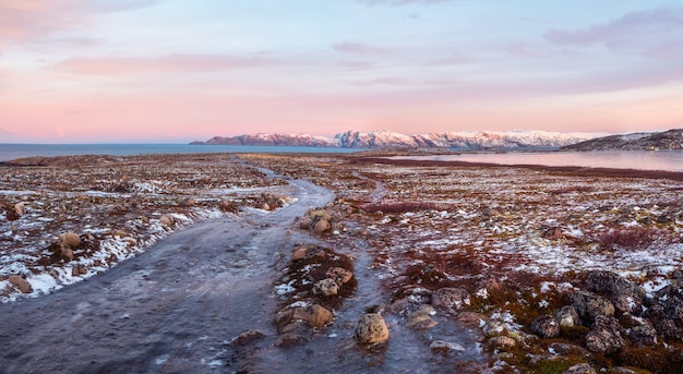 Strada invernale ghiacciata attraverso le colline della tundra a Teriberka. Meraviglioso paesaggio montano panoramico con tundra sul mare di Barents. Teriberka.