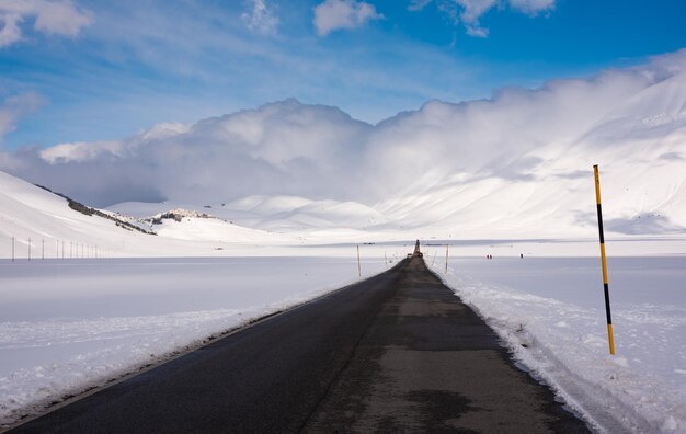 Strada invernale in una valle circondata da montagne coperte di neve