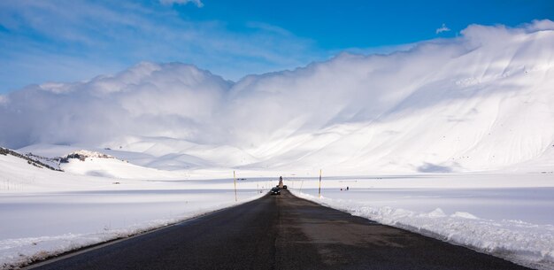 Strada invernale in una valle circondata da montagne coperte di neve