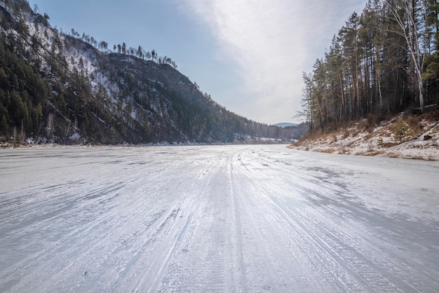 Strada invernale lungo il fiume mana ghiacciato in siberia pericolo di scioglimento dei ghiacci e pericolo di falli