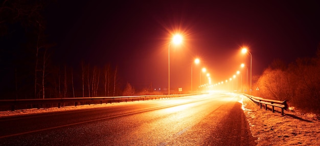 Strada notturna su lunga esposizione. Tracce di fari di automobili.