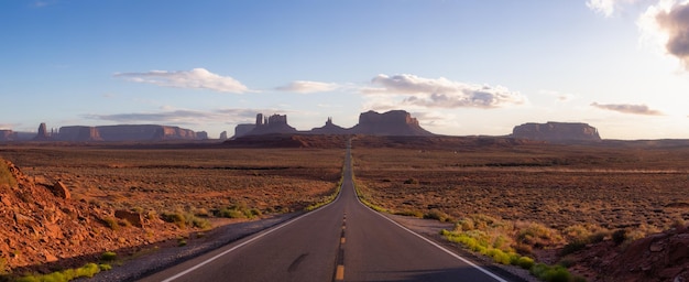 Strada panoramica nel deserto secco con montagne rocciose rosse sullo sfondo