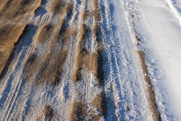 Strada pericolosa in inverno strada fangosa scivolosa con tracce di auto in inverno dopo la nevicata