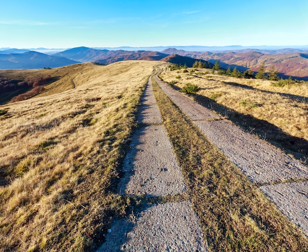 Strada rurale di lastre di cemento sul crinale in montagna d'autunno.