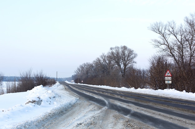 Strada scarsamente pulita invernale. Strada in campagna cosparsa di neve. Cumuli di neve