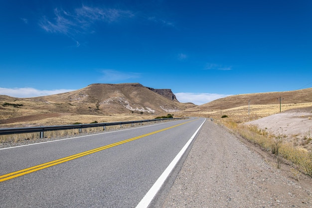 Strada solitaria e tranquilla che attraversa l'arido deserto sotto un cielo azzurro in una giornata molto calda