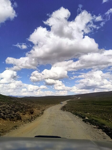 Strada sterrata con una macchina e un cielo nuvoloso