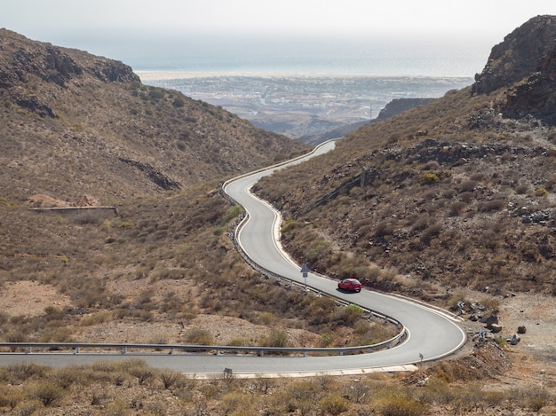 Strada tortuosa curva con un'automobile rossa nelle montagne in Gran Canaria