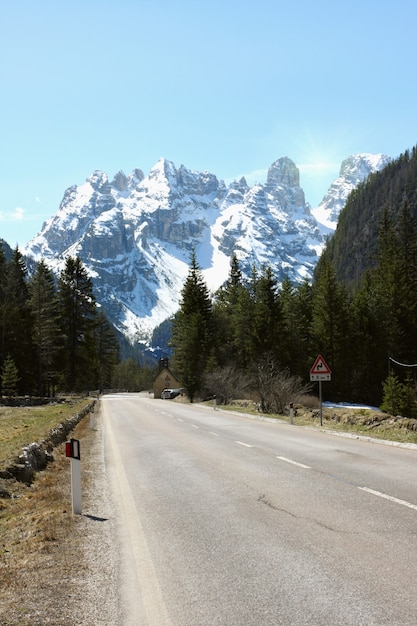 Strada tortuosa vuota verso le alte montagne innevate