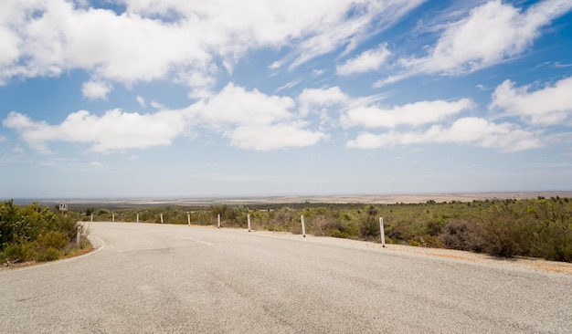 Strada verso il nulla con cielo azzurro e drammaticamente nuvoloso