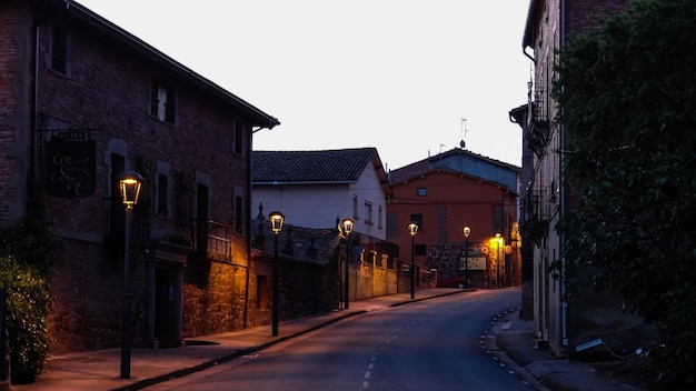 Strada vuota da lampioni illuminati in mezzo agli edifici al crepuscolo