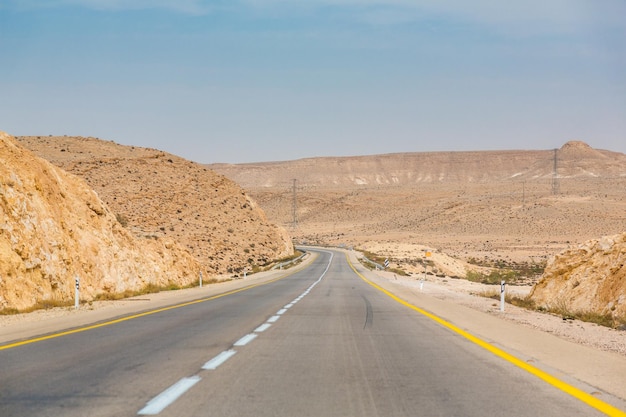 Strada vuota da qualche parte tra rocce e sabbie nel deserto del Negev vicino a Mitzpe Ramon in Israele