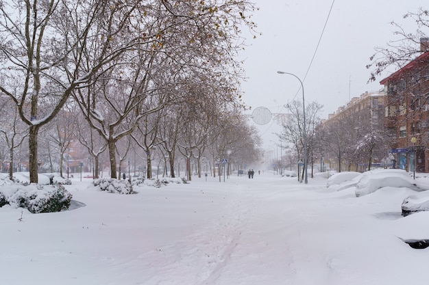 Strade ed edifici coperti di neve di giorno a causa della tempesta di neve Filomena che cade a Madrid in Spagna. Persone che camminano nella neve. Spagna