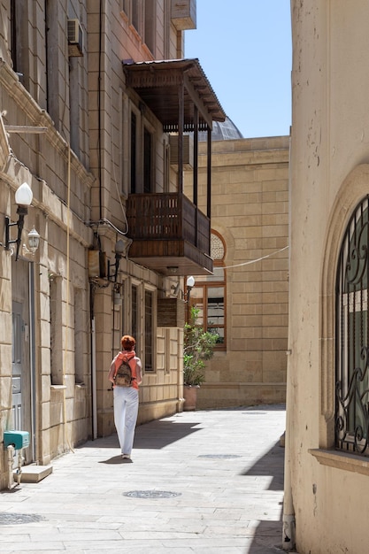 Stradina della città vecchia tra edifici in pietra scolpita con turisti femminili a piedi Baku Azerbaigian