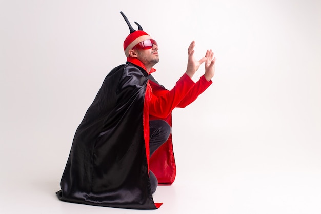 Strano uomo diabolico in occhiali da sole e costume di halloween rosso nero in posa